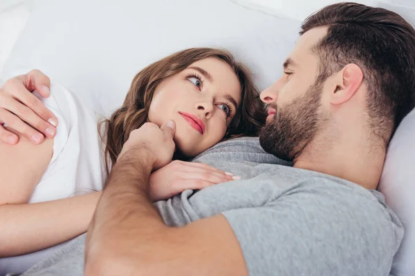 Adulto amoroso mujer gentil mirando en los ojos de hombre en cama - foto de stock