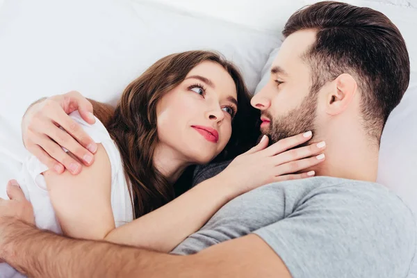 Junge liebende Frau sieht sanft in die Augen eines Mannes im Bett — Stockfoto