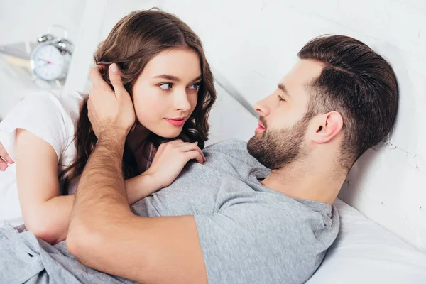 Adult loving couple gentle embracing and looking in eyes of each other in bed — Stock Photo