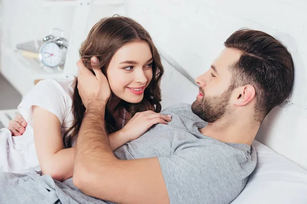Amorosa pareja gentil abrazándose y mirándose a los ojos en la cama - foto de stock