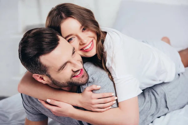 Enfoque selectivo de pareja amorosa joven abrazando y sonriendo en la cama - foto de stock