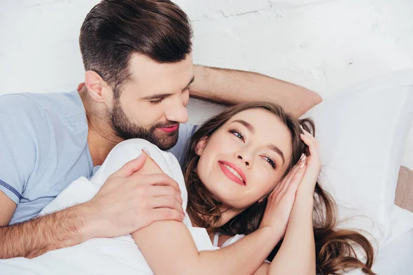 Young loving man gentle hugging woman in bed — Stock Photo