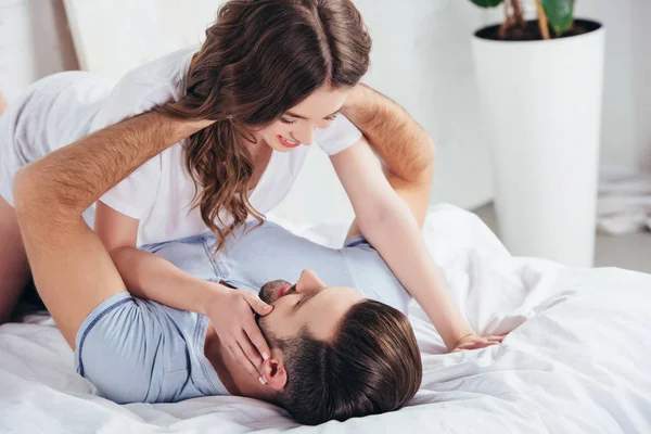 Selective focus of adult loving couple gentle hugging on white bedding — Stock Photo