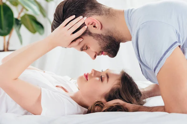 Enfoque selectivo de pareja amorosa joven suave abrazar y mirar a los ojos en la cama - foto de stock