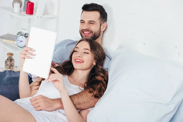 Jeune couple relaxant, souriant et utilisant une tablette numérique — Photo de stock