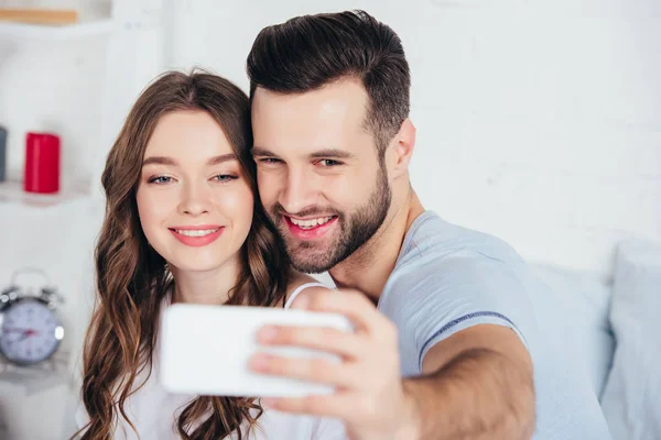 Selective focus of adult couple smiling and taking selfie — Stock Photo