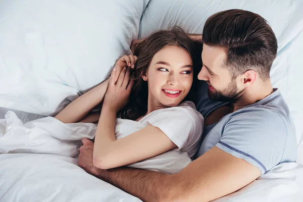 Jeune couple aimant câlin doux au lit et regardant dans les yeux — Photo de stock