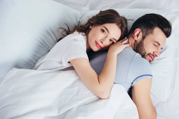 Young loving girlfriend gentle embracing boyfriend in bed — Stock Photo