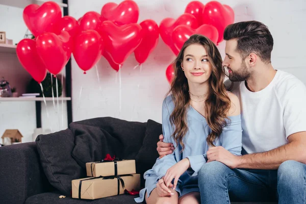 Glücklicher Mann schaut Frau im zum Valentinstag dekorierten Zimmer an — Stockfoto