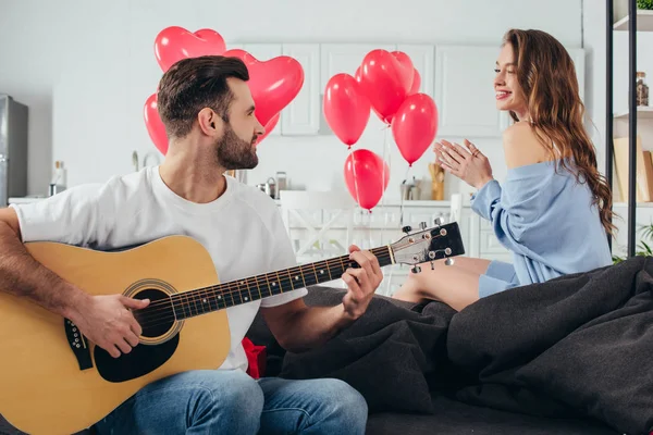 Amorosa pareja celebrando San Valentín mientras joven tocando la guitarra acústica - foto de stock