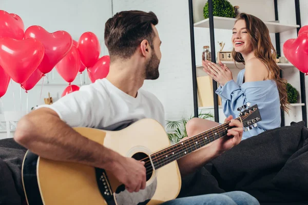 Glückliches Paar feiert Valentinstag, während junger Mann Akustikgitarre spielt — Stockfoto