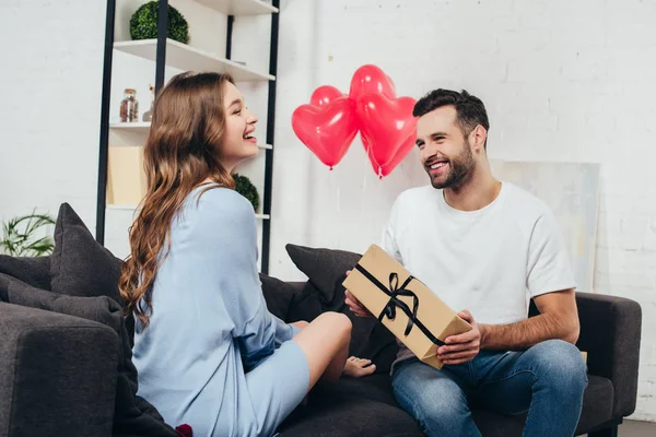 Young man presenting gift box to girlfriend at valentines day — Stock Photo