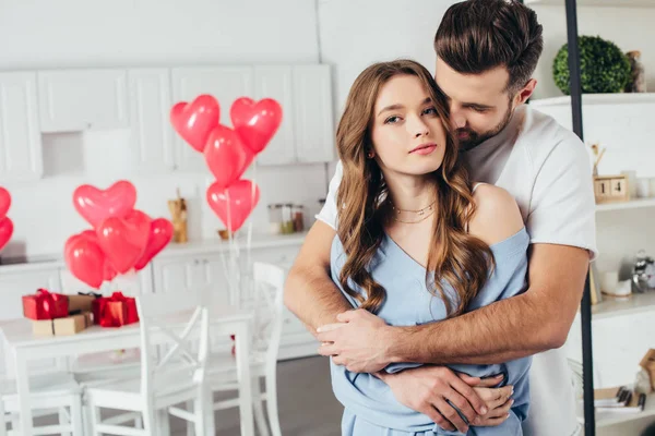 Selective focus of happy girl embraced by boyfriend at home in room decorated for st valentine day — Stock Photo