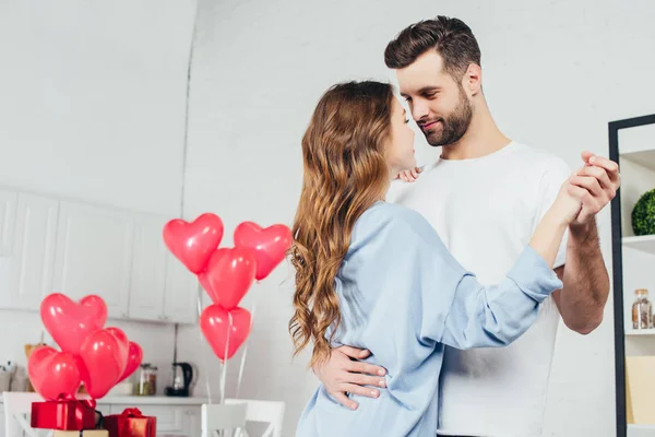 Casal feliz dançando em casa no quarto decorado com balões em forma de coração — Fotografia de Stock