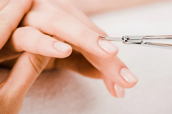 Vista recortada de la manicura usando tijeras de manicura para eliminar la cutícula - foto de stock