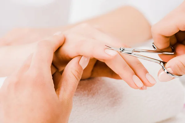Vista ritagliata della manicure che tiene delicatamente la mano mentre taglia la cuticola — Foto stock