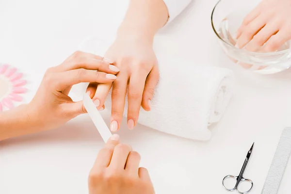 Cropped view of manicurist filing nails with nail file — Stock Photo