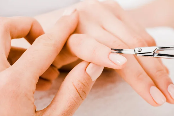 Cropped view of manicurist using manicure scissors to remove cuticle — Stock Photo