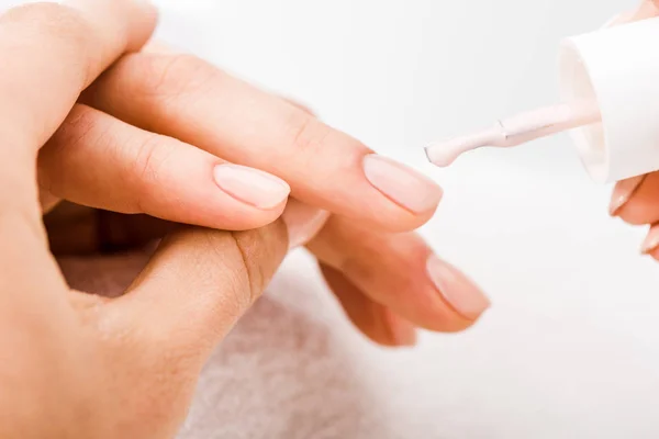 Vista cortada da mão manicure segurando e aplicando esmalte nas unhas — Fotografia de Stock