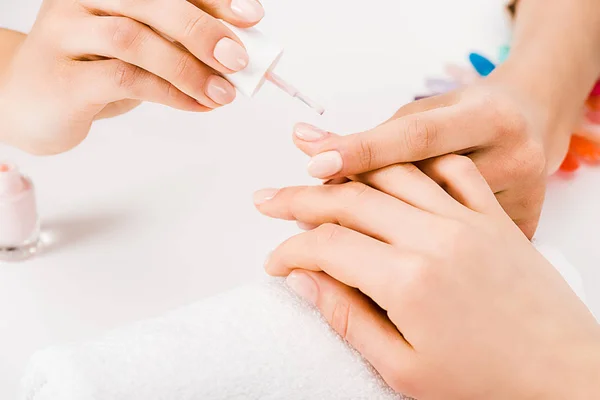 Vista parcial da manicure segurando suavemente a mão durante a aplicação de esmalte — Fotografia de Stock