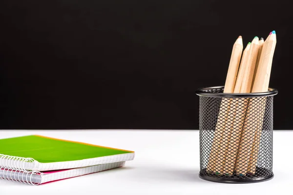 Pencils and notebooks isolated on black with copy space — Stock Photo