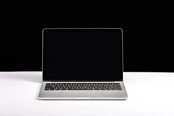 Laptop with blank screen on white desk isolated on black — Stock Photo