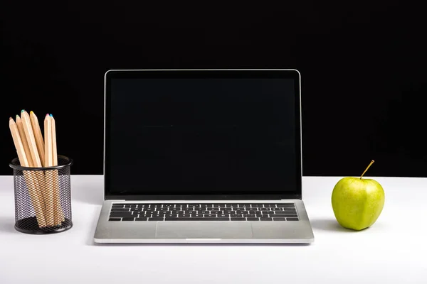 Manzana, portátil con pantalla en blanco y lápices aislados en negro - foto de stock