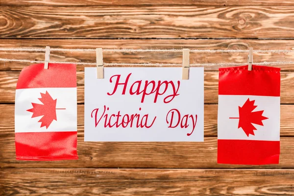 Vista superior de bandeiras canadenses e cartão com letras 'happy victoria day' em fundo de madeira — Fotografia de Stock