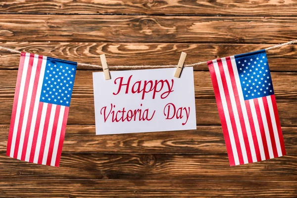 Vista superior de banderas americanas y tarjeta con letras de 'feliz día de la victoria' sobre fondo de madera - foto de stock
