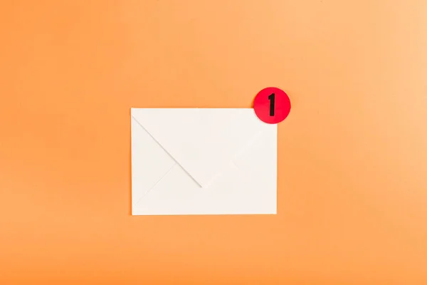 Вид зверху паперового конверта з червоним колом і сповіщенням з номером 1 ізольовано на помаранчевому — стокове фото