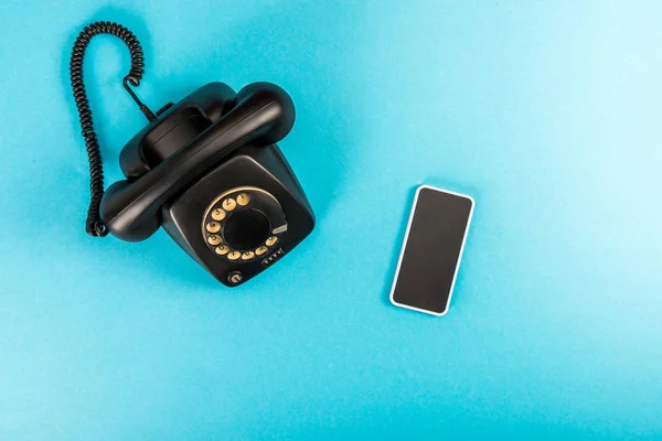 Top view of rotary dial telephone and smartphone with copy space isolated on blue — Stock Photo