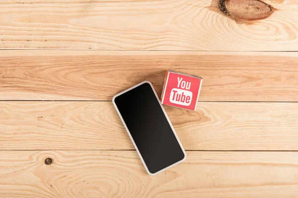 Vista superior del icono de youtube y teléfono inteligente con pantalla en blanco en la mesa de madera - foto de stock