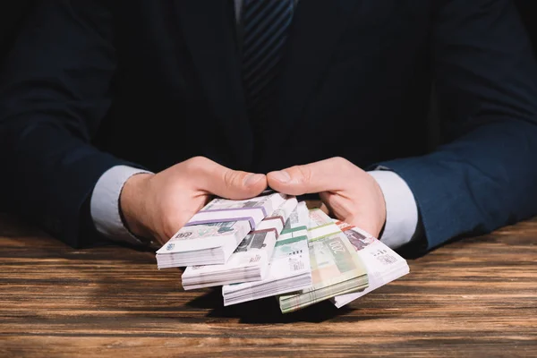 Abgeschnittene Aufnahme eines Geschäftsmannes mit russischen Rubel-Banknoten über Holztisch — Stockfoto