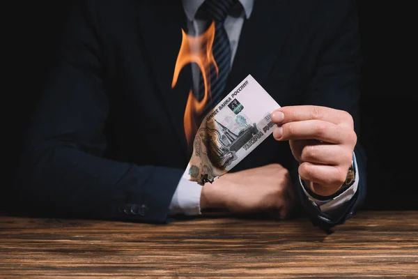 Plan recadré de l'homme d'affaires brûlant des roubles russes billet de banque au-dessus de la table en bois — Photo de stock