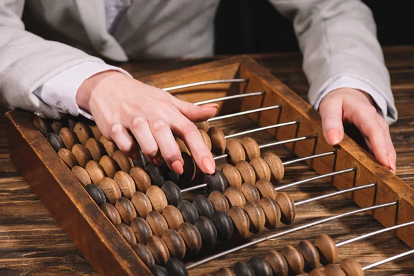 Cropped shot of businesswoman using counting frame at wooden table — Stock Photo