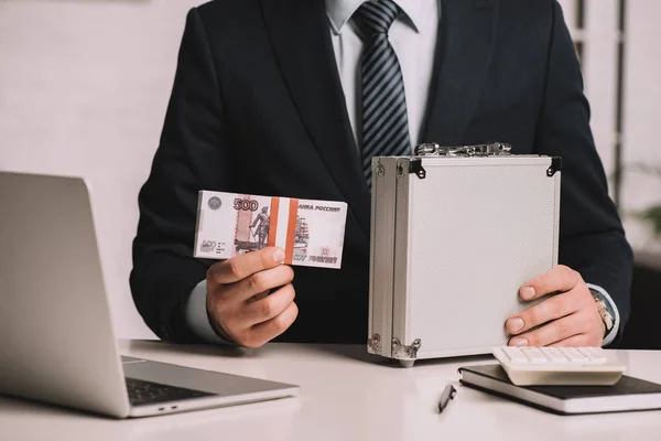 Plan recadré de l'homme d'affaires tenant coffre-fort valise et des billets de banque roubles russes sur le lieu de travail — Photo de stock