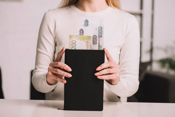 Cropped shot of woman holding notebook with russian rubles banknotes — Stock Photo