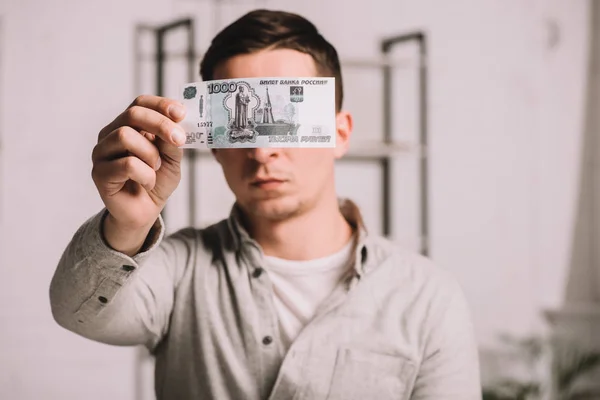 Young man hiding face behind russian rubles banknote — Stock Photo