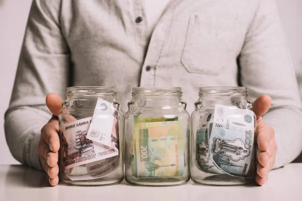 Обрізаний знімок чоловік тримає скляні банки з російських рублів банкнот — стокове фото