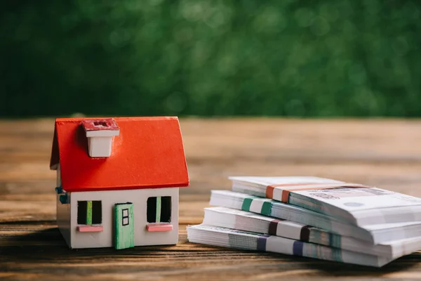 Vue rapprochée du modèle de petite maison et des billets de banque en roubles russes sur une table en bois — Photo de stock