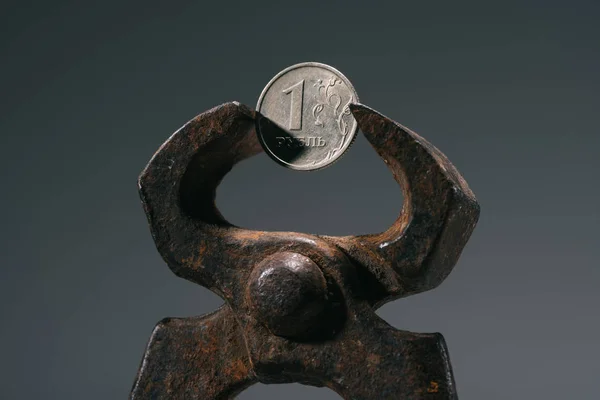 Vue rapprochée de l'outil d'étau de fer avec une pièce de monnaie en rouble isolé sur gris — Photo de stock