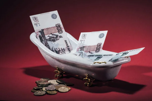 Roubles russes billets en petite baignoire et pièces sur rouge, concept de blanchiment d'argent — Photo de stock
