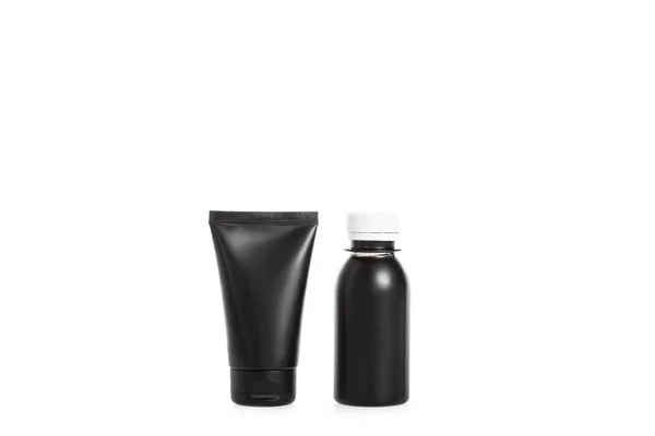 Studio shot of black cream tube and little plastic bottle isolated on white — Stock Photo