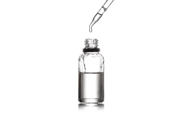 Студийный снимок стеклянной бутылки и пипетки с каплей жидкости, изолированной на белом — стоковое фото