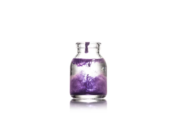 Estudio plano de frasco de vidrio con agua y salpicadura púrpura aislado en blanco - foto de stock