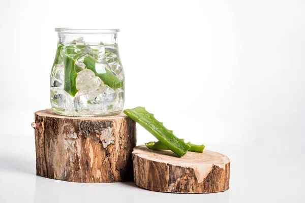 Photo studio de pot en verre avec glaçons et feuilles d'aloe vera — Photo de stock