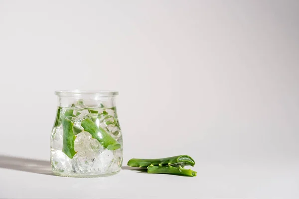 Estúdio tiro de frasco de vidro contendo folhas de aloe vera e gelo — Fotografia de Stock