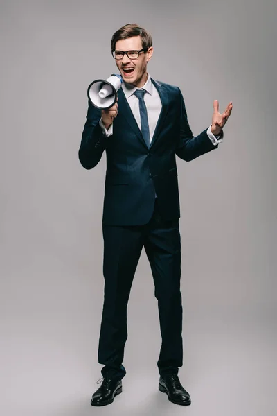 Angry businessman in suit screaming in megaphone isolated on grey — Stock Photo