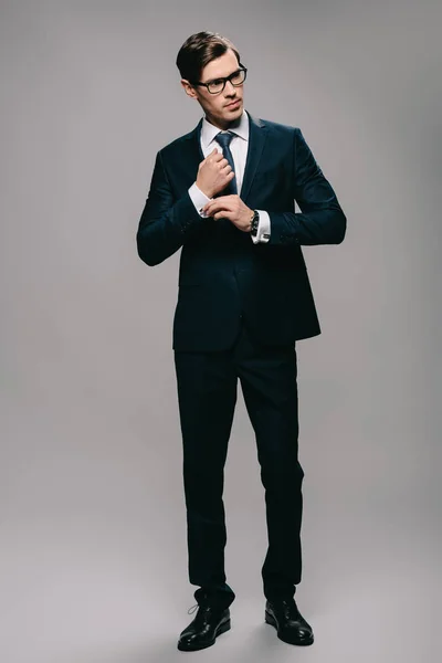 Впевнений бізнесмен стоїть в костюмі на сірому фоні — стокове фото