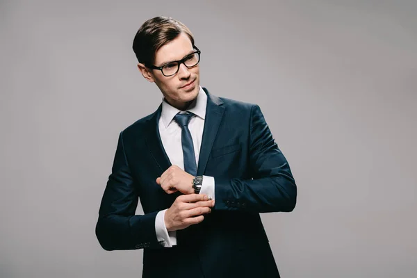 Seriöser Geschäftsmann steht im Anzug vor grauem Hintergrund — Stockfoto